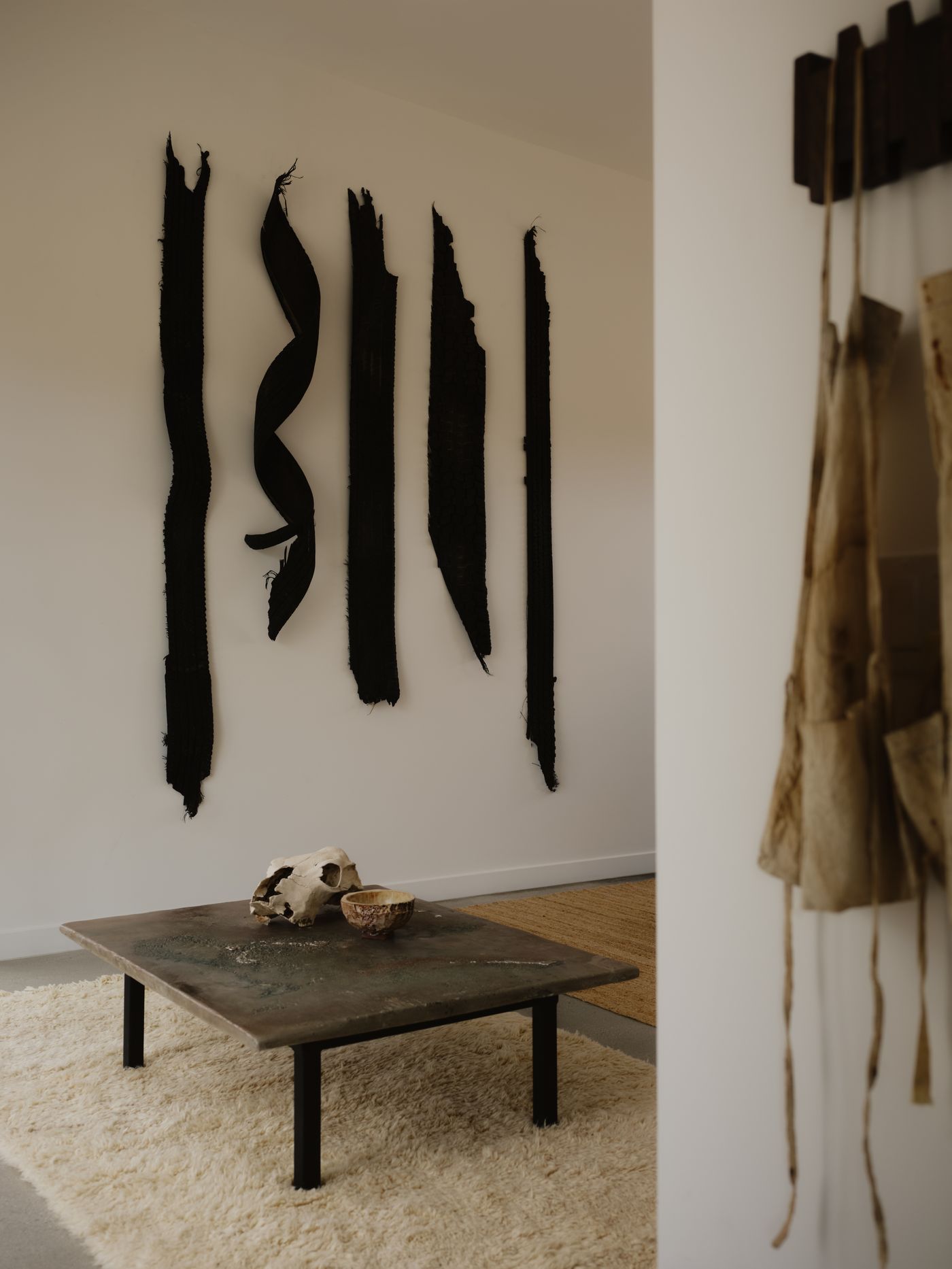 Dark textile works hung above a low table