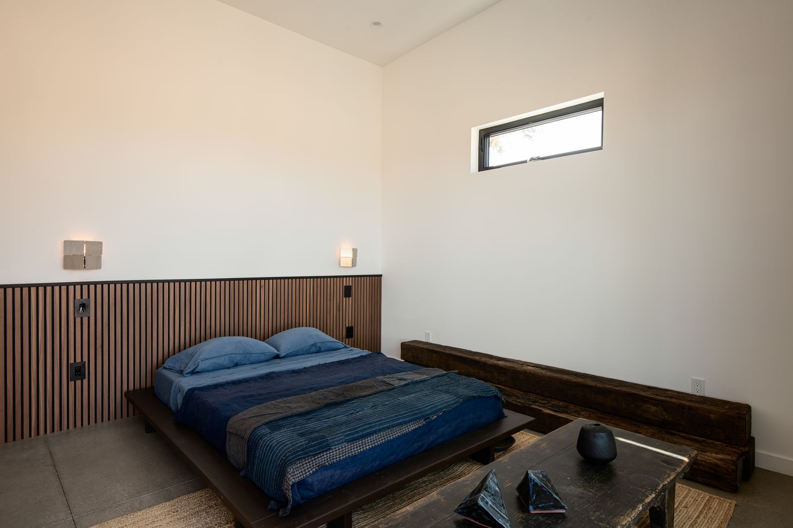 Bedroom with indigo linens and walnut slat wall