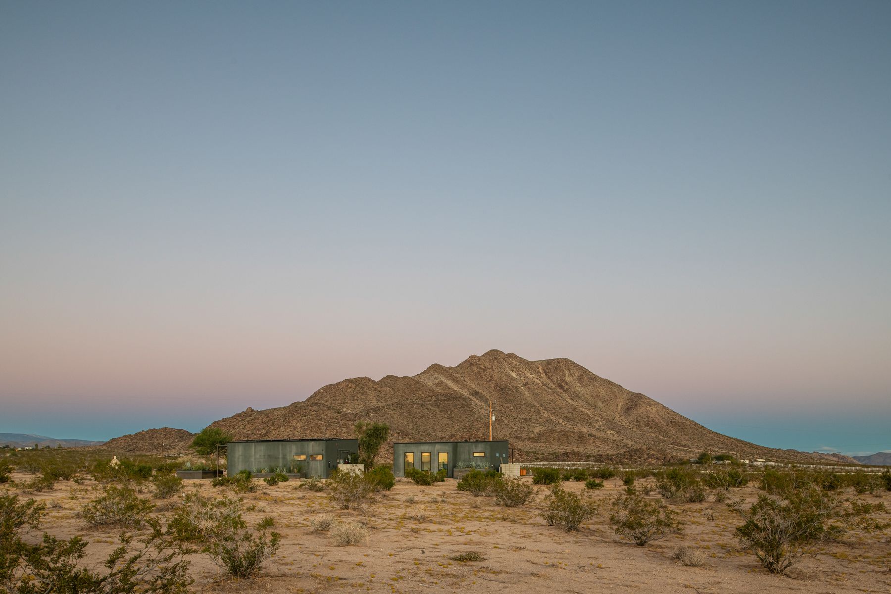 The compound small against the Mojave at dusk