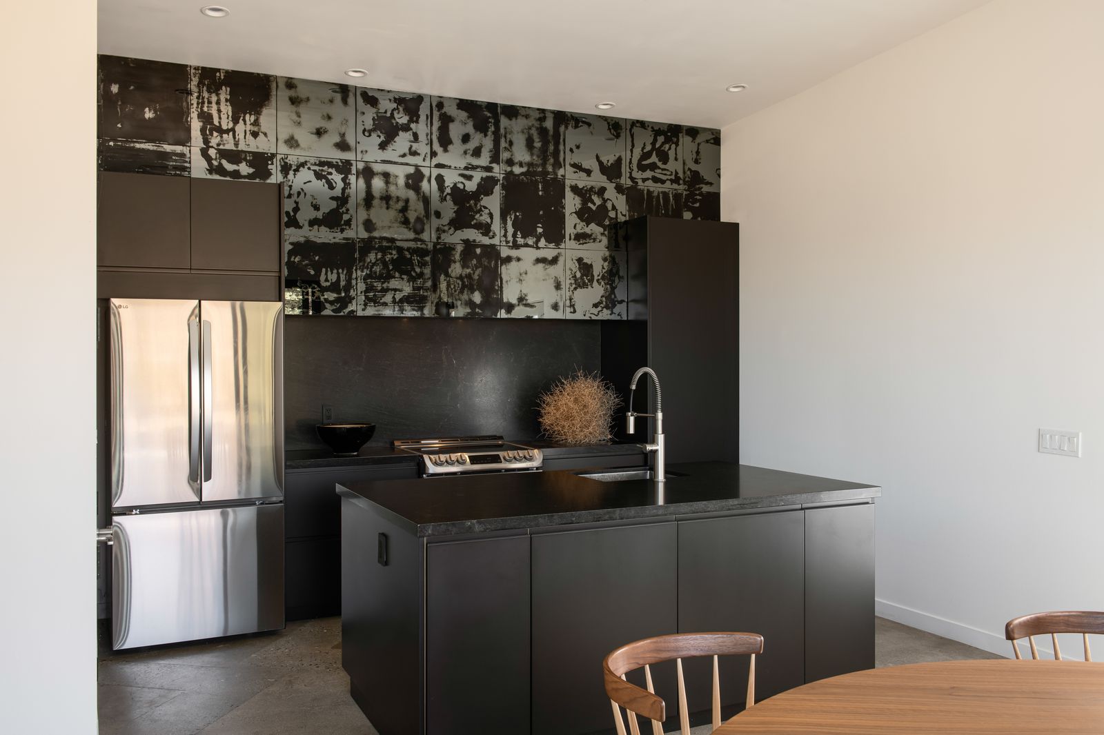 Dark kitchen island with patinated steel backsplash